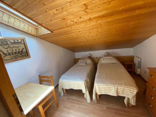 deux lits dans une chambre avec un plafond en bois dans l'établissement Appartement cosy au cœur de La Clusaz - 6 pers, balcon et garage, proche commerces et ski. - FR-1-459-32, à La Clusaz
