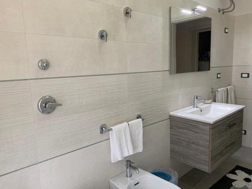 a white bathroom with a sink and a mirror at Dimoramare in Tonnara di Bonagia