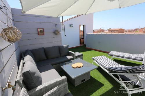 a patio with a couch and a table and an umbrella at Casa Feliz - Penthouse in San Pedro del Pinatar 100m from shops & 500m from beach & boulevard in San Pedro del Pinatar