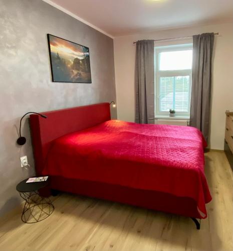 a red bed in a bedroom with a window at Berta's Apartments in Děčín