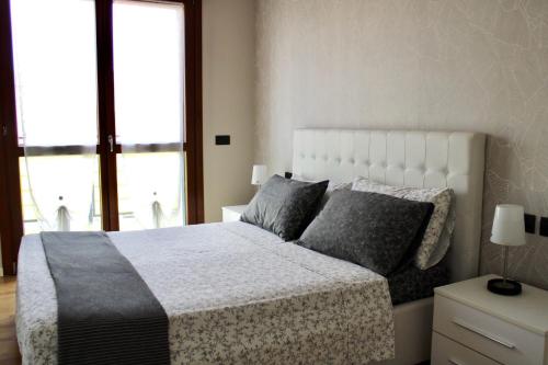 1 dormitorio con 1 cama blanca grande con almohadas grises en Rho Fiera Milano - Popy House en Pero