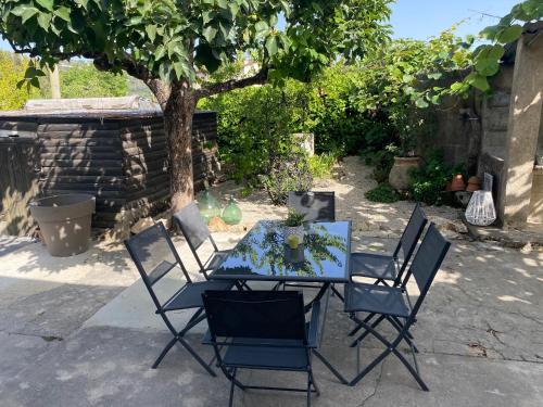 a table and chairs in a yard with a tree at La Bastide de Jean Maison de charme dans un domaine equestre privé in Grasse