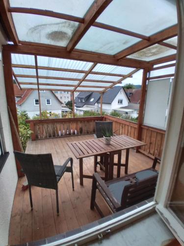 a screened in patio with a wooden table and chairs at Ferienhaus in großem Garten in Bad Sooden-Allendorf