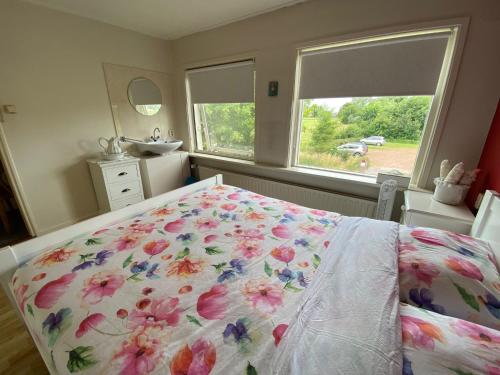 a bedroom with a bed with a floral bedspread at Huis bij het water in uitstekend fiets-, vis- en vaargebied in Jutrijp