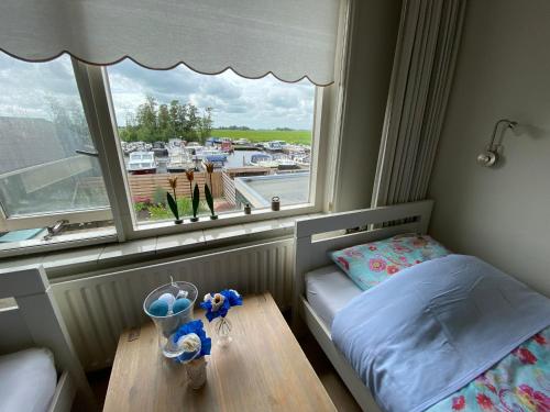 a small bedroom with a window and a table at Huis bij het water in uitstekend fiets-, vis- en vaargebied in Jutrijp
