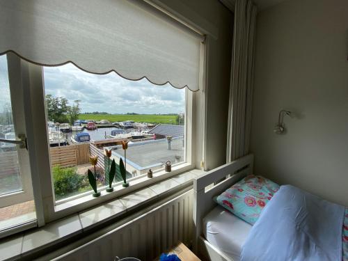 een slaapkamer met een raam met uitzicht op een jachthaven bij Woning aan het water in het Friese Merengebied in Jutrijp