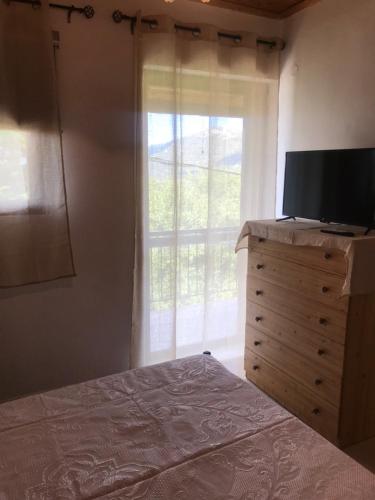 a bedroom with a bed and a television on a dresser at Gourgiana Apartments in Andritsaina