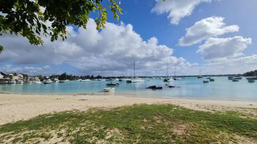 a group of boats in the water on a beach at Beachfront penthouse with panoramic ocean view in Grand Baie