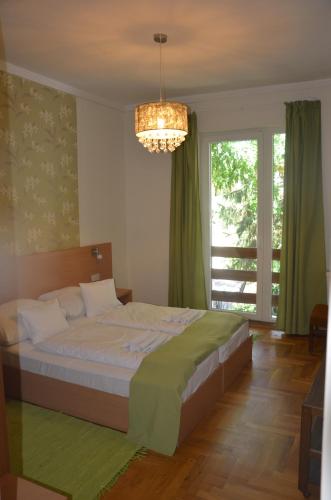 a bedroom with a large bed and a chandelier at Hotel Viktória in Balatonalmádi