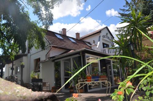 a white house with a table in front of it at Hotel Viktória in Balatonalmádi