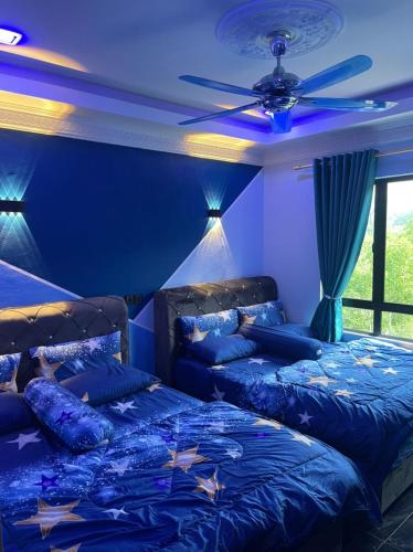 Cette chambre bleue comprend 2 lits et un ventilateur de plafond. dans l'établissement Sunshine Bay Resort Beachaholic Homestay, à Port Dickson