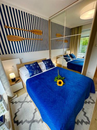 a bedroom with a blue bed with a sunflower on it at Apartament Nadmorski Hampton in Kołobrzeg