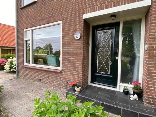 a brick house with a black door and a window at Huis bij het water in uitstekend fiets-, vis- en vaargebied in Jutrijp