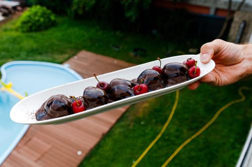 a person holding a plate with chocolate and cherries on it at Pensiunea Decebal Resort - Cazanele Dunarii in Dubova