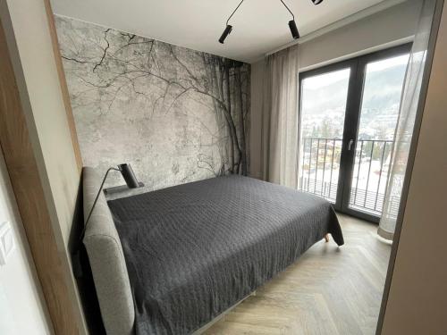 sypialnia z łóżkiem i dużym oknem w obiekcie Apartament blisko kolejki na Skrzyczne w Szczyrku
