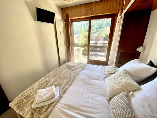 a large bed in a room with a large window at Sunny mountain view apartment in town by Jolidi in Nendaz
