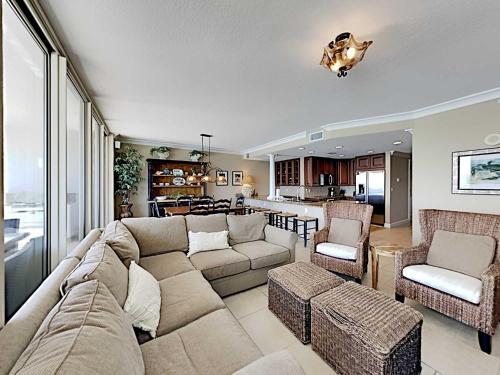Una sala de estar con un sofá y sillas y una cocina. en Beach Club #904C, en Pensacola Beach
