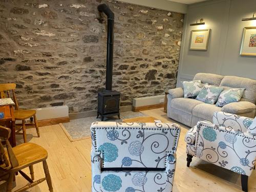 a living room with a stone wall and a stove at Century Old Shepherds Cottage overlooking Loch Tay in Aberfeldy