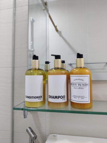 three bottles of soap on a shelf above a sink at Chic Hideaway at Azure North Bali Tower in San Fernando