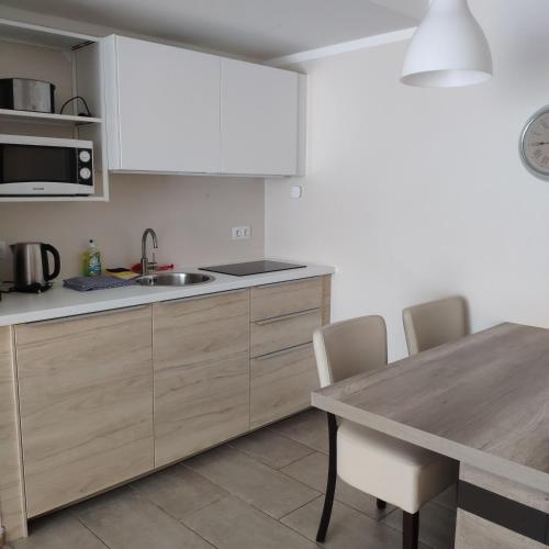 a kitchen with white cabinets and a wooden table at Hotel Lindenhof in Bad Gastein