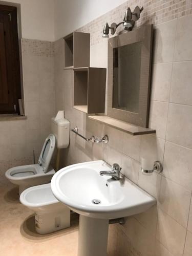 a bathroom with a white sink and a toilet at Bikini Patti beach in Patti