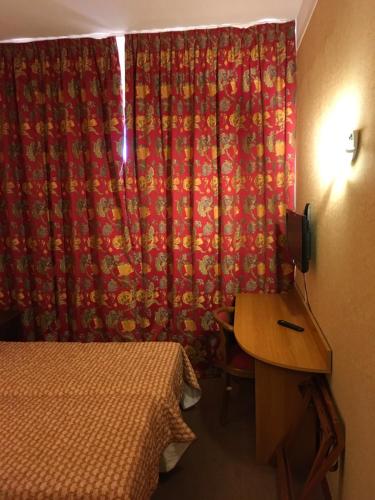 a room with a bed and a red curtain at Hotel Dorele in Montargis