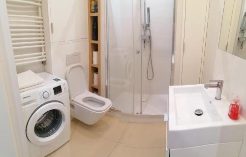 ein weißes Badezimmer mit einer Waschmaschine und einem Waschbecken in der Unterkunft Apartamenty Warszawskie delux Siedmiogrodzka in Warschau