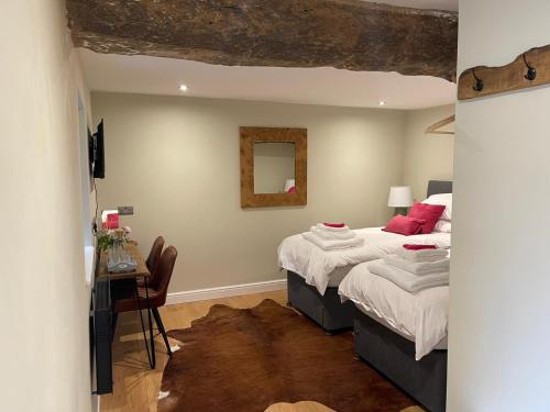 a bedroom with two beds and a table and a mirror at Trouble House in Tetbury