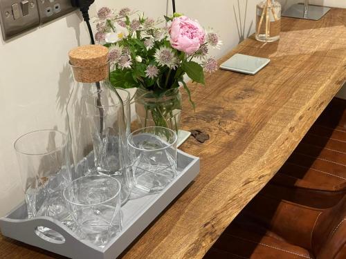 a table with glasses and a vase with flowers at Trouble House in Tetbury