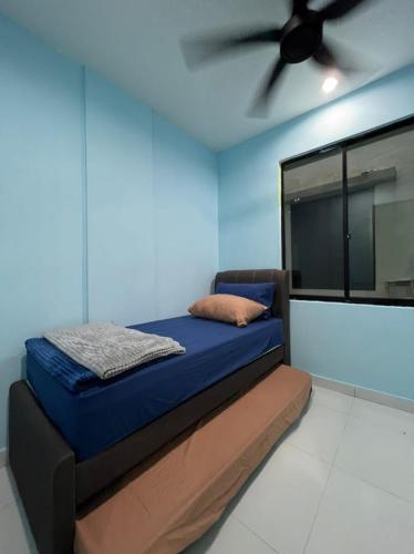Cama en habitación con ventilador de techo en FAIZ HOMESTAY, en Kuching