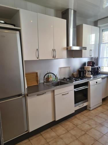 une cuisine avec des armoires blanches et des appareils en acier inoxydable dans l'établissement Maison de pêcheur typique proche plage, à Fécamp