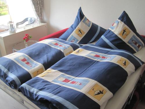 ein Bett mit blauer Bettwäsche und Kissen darauf in der Unterkunft Apartment Marina Wendtorf in Wendtorf