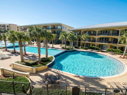 a large swimming pool with palm trees in front of a building at Adagio #203E in Santa Rosa Beach