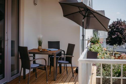 a table and chairs on a balcony with an umbrella at AusZeit Neusiedlersee in Mörbisch am See