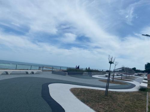 a walkway next to the beach with the ocean at Vila Eric in Eforie Sud