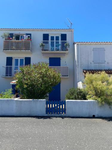 a white building with a blue door and some bushes at Appartement vue mer in La Guérinière