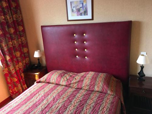 a bedroom with a bed with a red head board at Hotel Dorele in Montargis