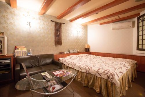 a room with a bed and a chair and a glass table at ファインリゾート in Nagoya