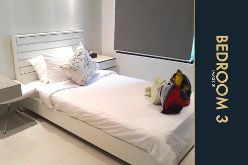 a bed with white sheets and pillows and a desk at 3 BR Stylish Condo with Private Rooftop Pool in Kamala Beach