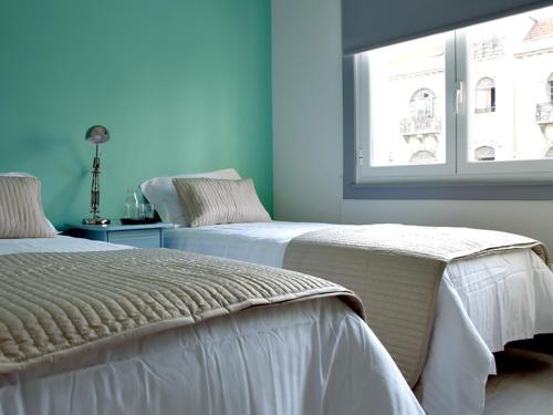2 łóżka w pokoju z niebieskimi ścianami i oknem w obiekcie Ey Lisbon GuestHouse w Lizbonie