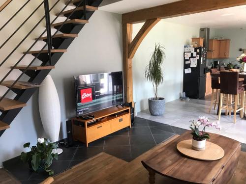 a living room with a television and a staircase at CHAMBRE La Petite VENISE in Pont-Audemer