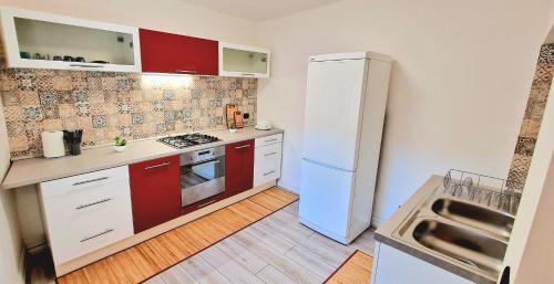 uma cozinha com um frigorífico branco e armários vermelhos em La Casetta del Vicolo em Narni