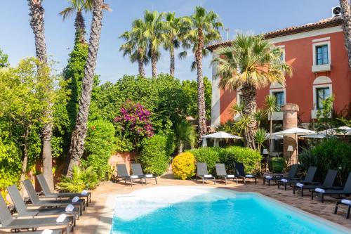 a resort pool with chairs and palm trees at Hôtel l'Arena in Fréjus