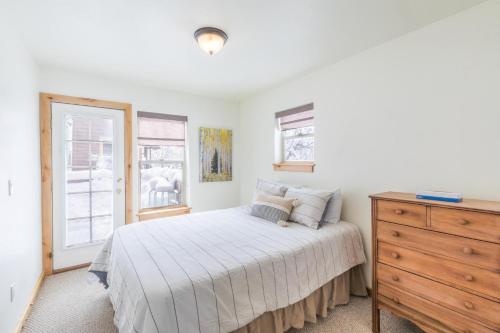 a white bedroom with a bed and a dresser at Alpenglow Unit 6 in Ouray