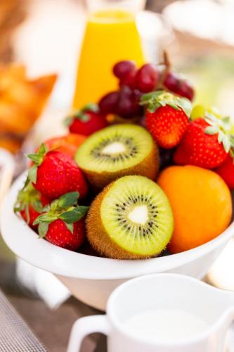 a bowl of fruit with strawberries kiwis and oranges at Hôtel l'Arena in Fréjus