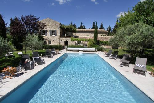 une piscine avec des chaises et une maison dans l'établissement Le Mas du Père Jean, à Roche-Saint-Secret