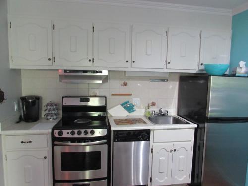 una cocina con armarios blancos y electrodomésticos de acero inoxidable en Superbe condo bord de l'eau à Magog, en Magog-Orford