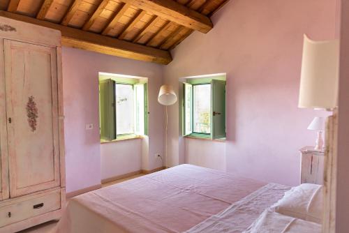 a bedroom with a white bed and two windows at Il casale dei nonni in Grottazzolina