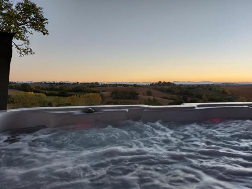 une baignoire jacuzzi avec vue sur le coucher du soleil en arrière-plan dans l'établissement Les Gîtes de LAURES, à Monblanc
