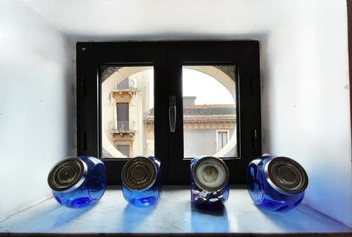 une fenêtre avec quatre vases bleus sur le rebord de la fenêtre dans l'établissement DOMUS COPPOLA CATANIA Apartments, à Catane